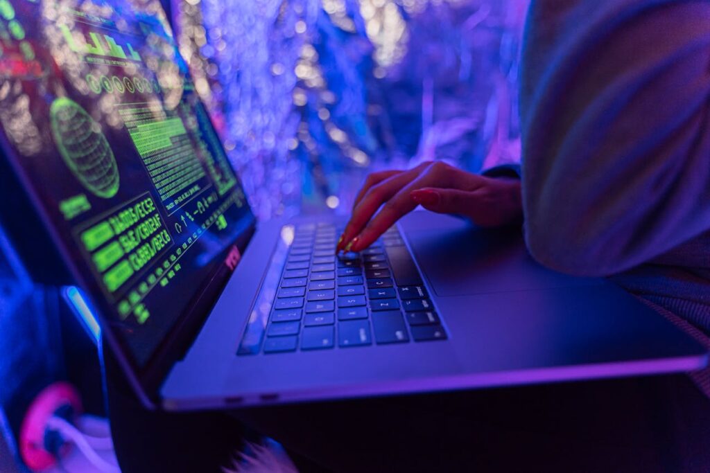 Mains sur un clavier d’ordinateur portable affichant des lignes de code